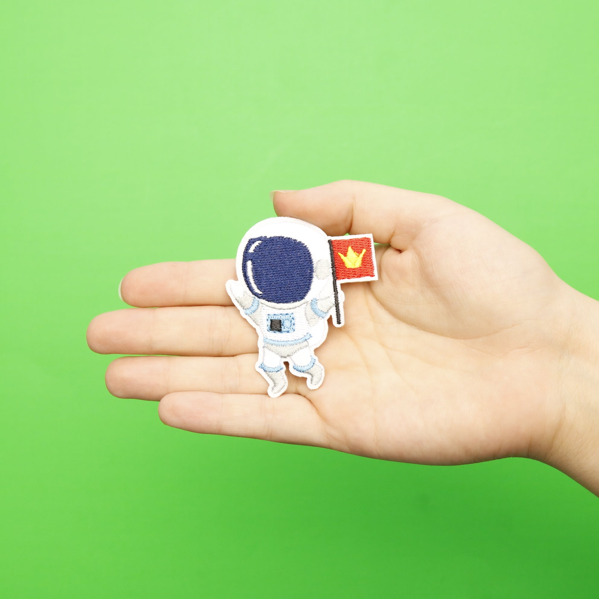 Small Blue Astronaut Holding A Red Flag With Gold Crown Embroidered Iron On Patch